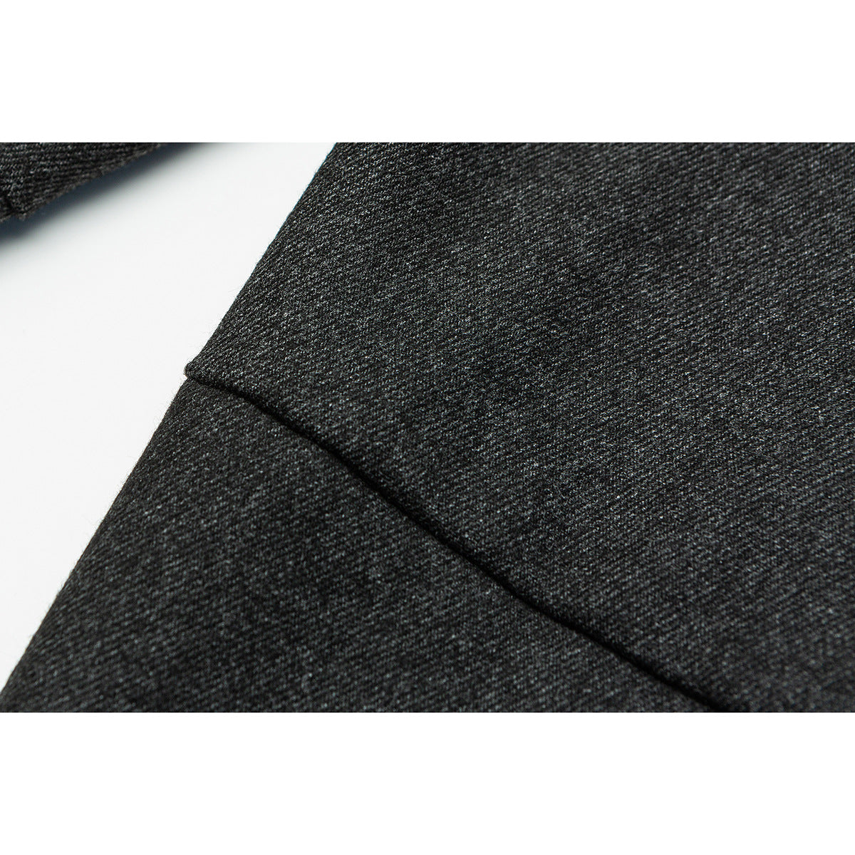 Extreme close-up of charcoal gray trouser fabric and a diagonal stitched seam.