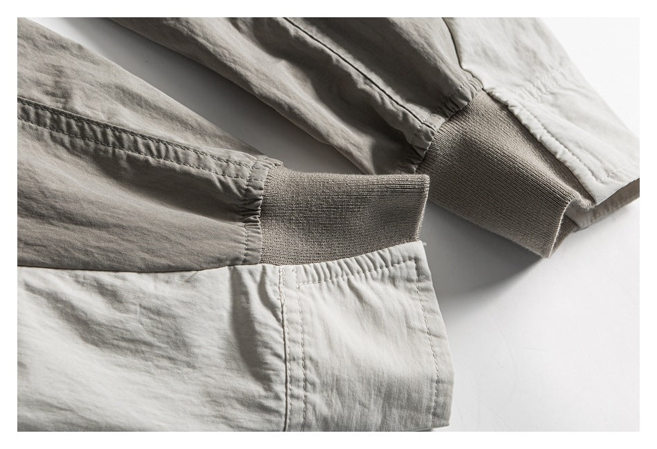 Close-up of two ribbed cuffs and stitched garment edges in light neutral tones.