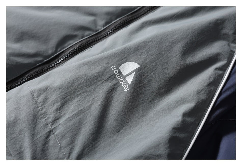 Close-up of a gray jacket panel with a zipper, white piping, and a small white logo.