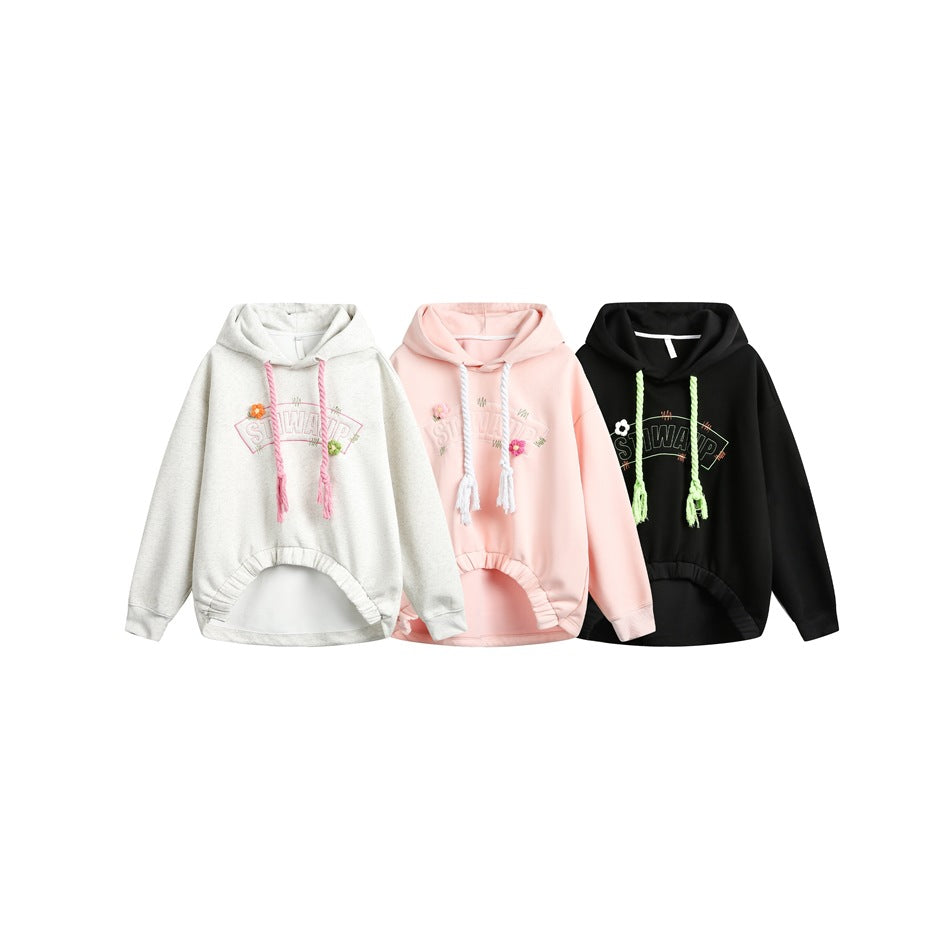 Three oversized hoodies shown together in light gray, pale pink, and black, each with colorful drawstrings and chest