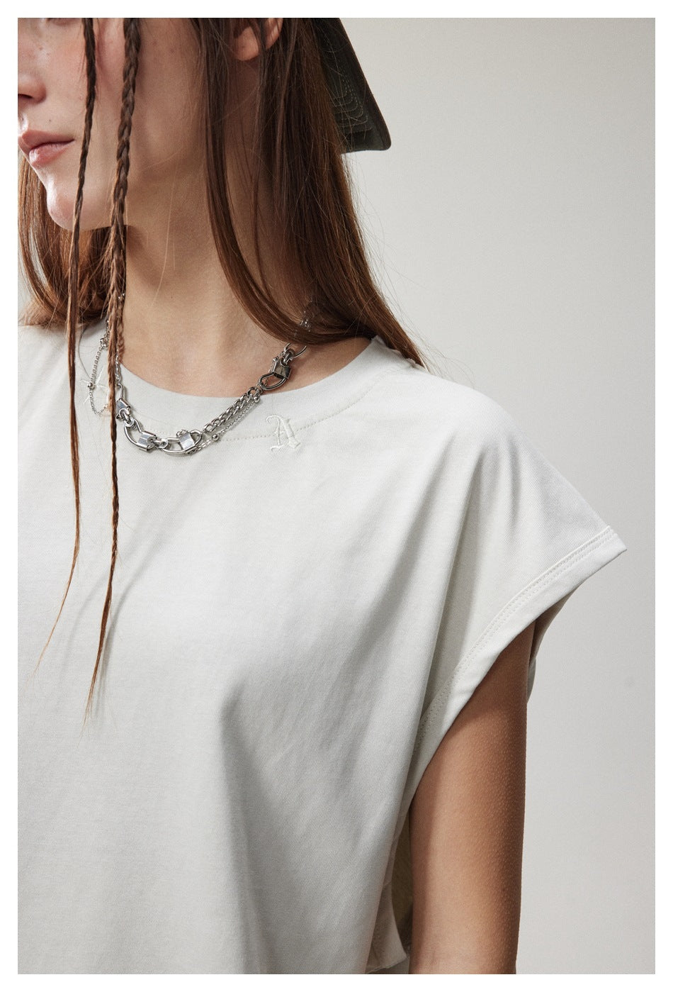 Close-up of the white top's neckline, shoulder seam, and small embroidered chest emblem.