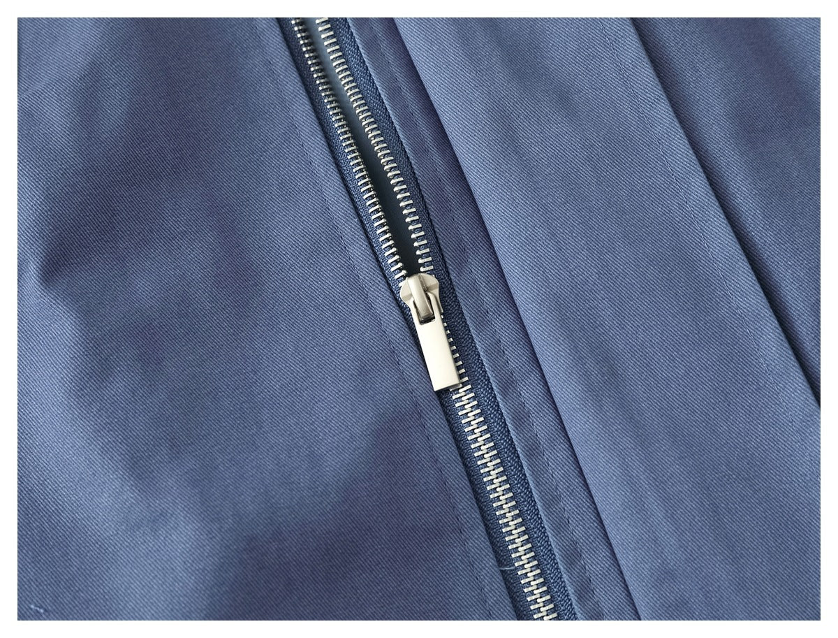 Close-up of a silver zipper and stitching on blue fabric.