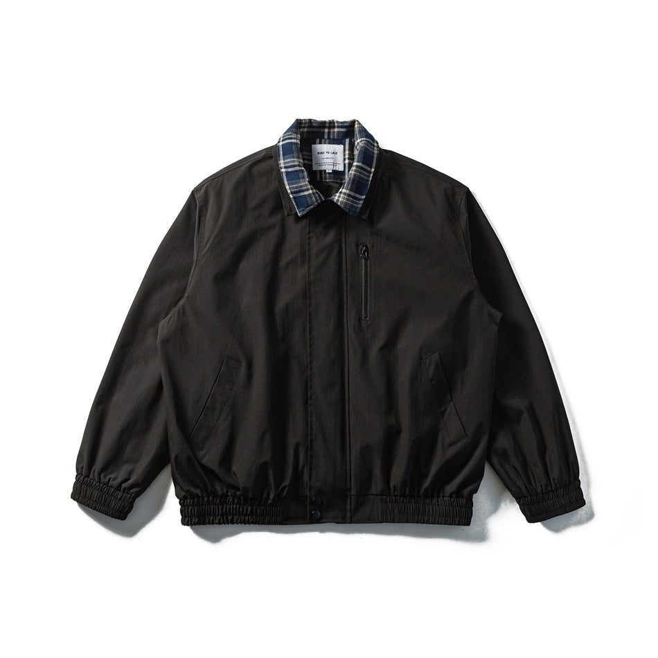 Black collared jacket with navy plaid collar, zip chest pocket, slanted pockets and elastic cuffs and hem, flat lay