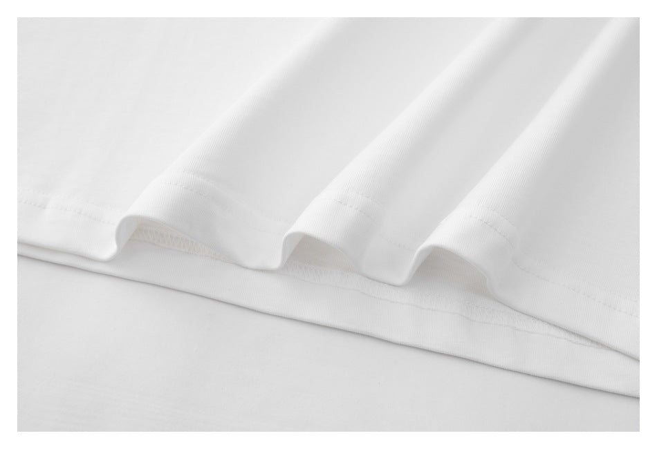 Close-up of the white T-shirt’s stitched bottom hem and folded fabric.
