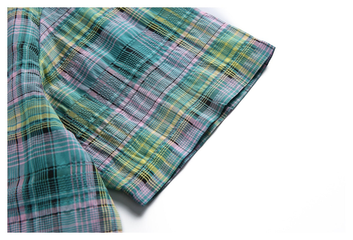 Close-up of a plaid shirt sleeve and cuff in teal, pink, yellow, and black.