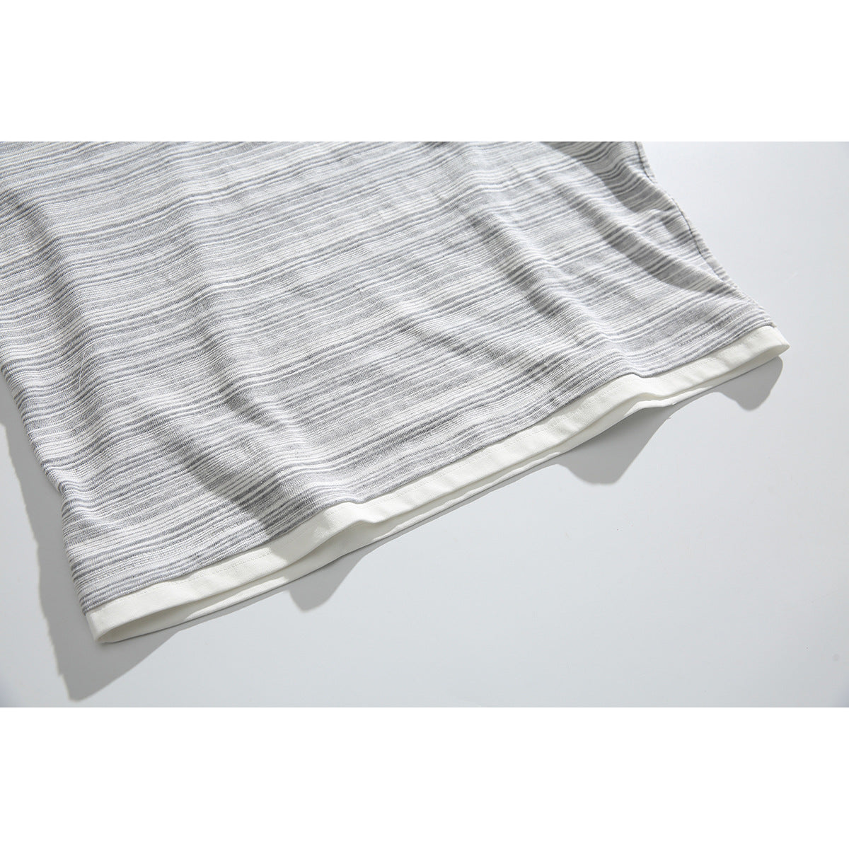 Close-up of the gray-and-white striped shirt hem layered over a white inner hem.