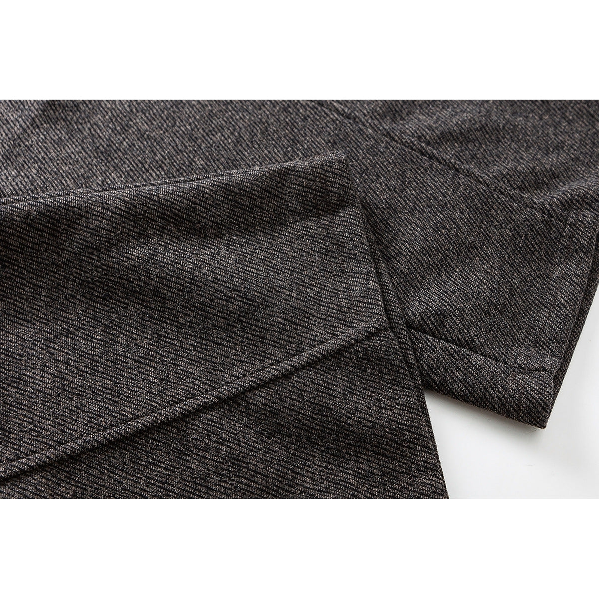 Close-up of heathered brown trousers showing overlapping fabric and a stitched seam.