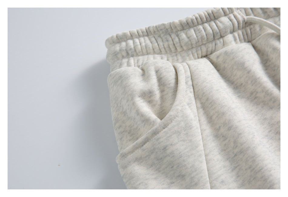 Close-up of light gray marled joggers showing the elastic waistband and angled pocket opening.
