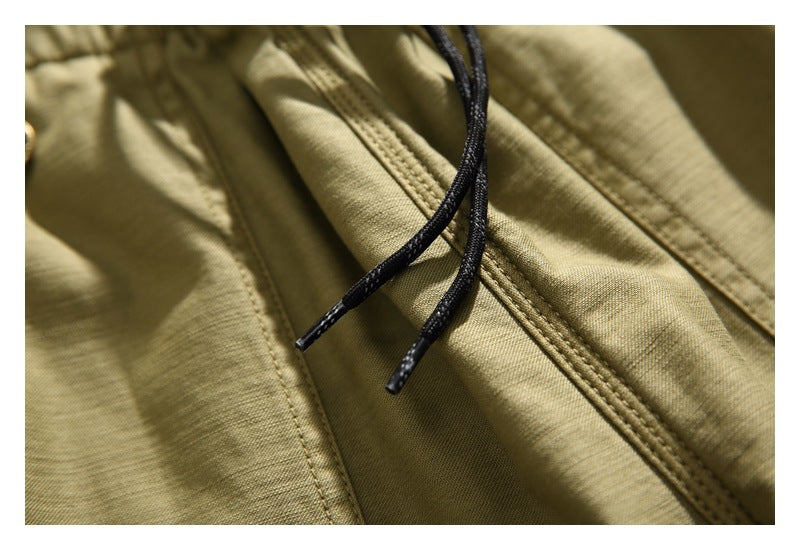 Close-up of khaki shorts with black drawcords and prominent double-stitched seams.
