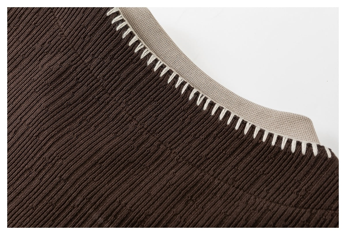 Close-up of a dark brown ribbed knit neckline with beige trim and white contrast stitching.