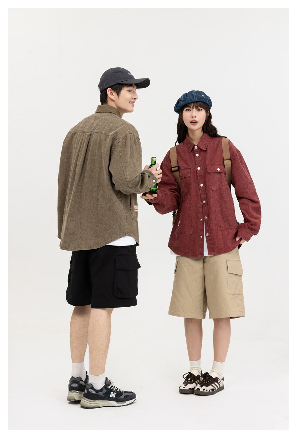 A man shows the back of an olive shirt beside a woman wearing a burgundy button-front shirt with pockets.