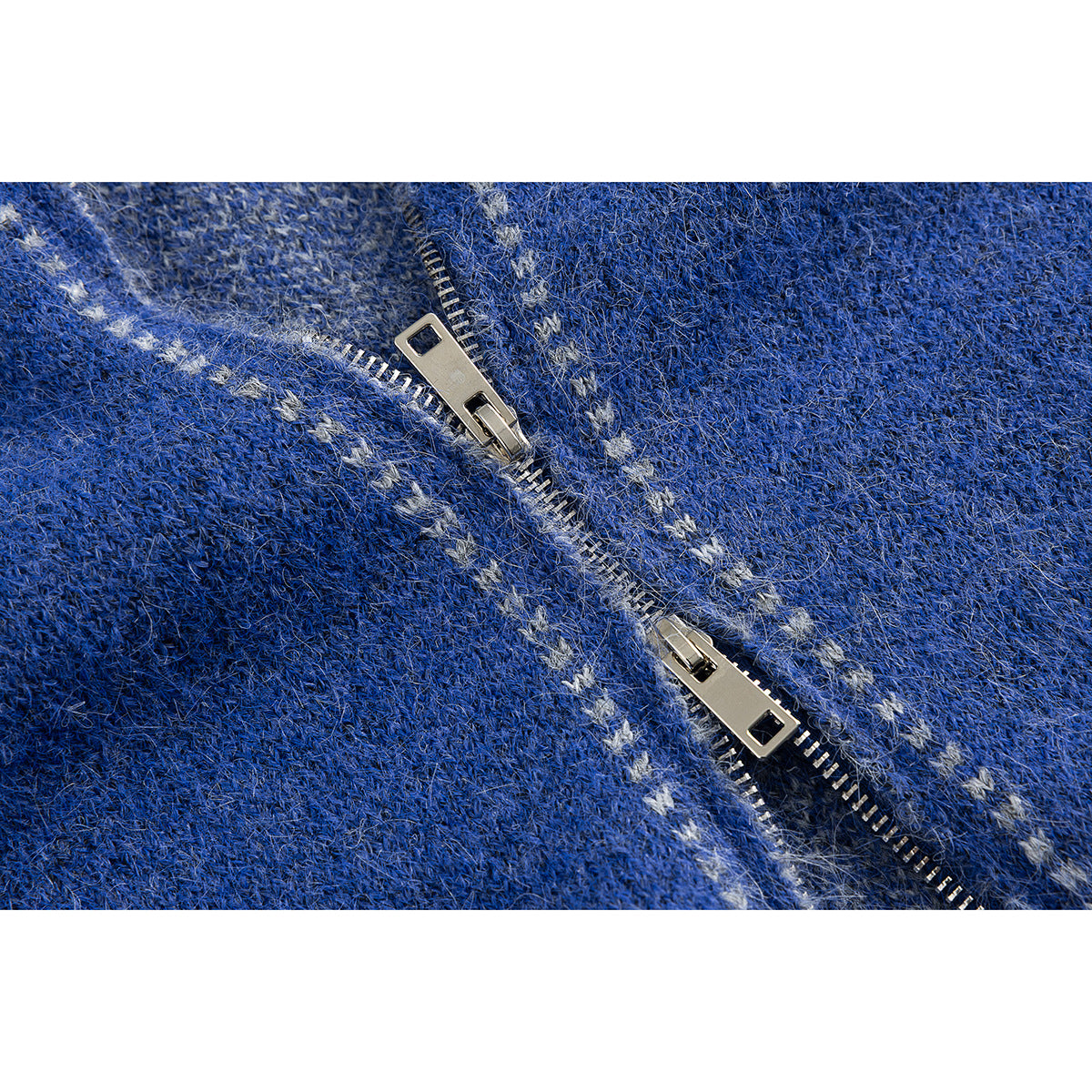 Close-up of a silver zipper on blue knit fabric with small light-colored motifs.