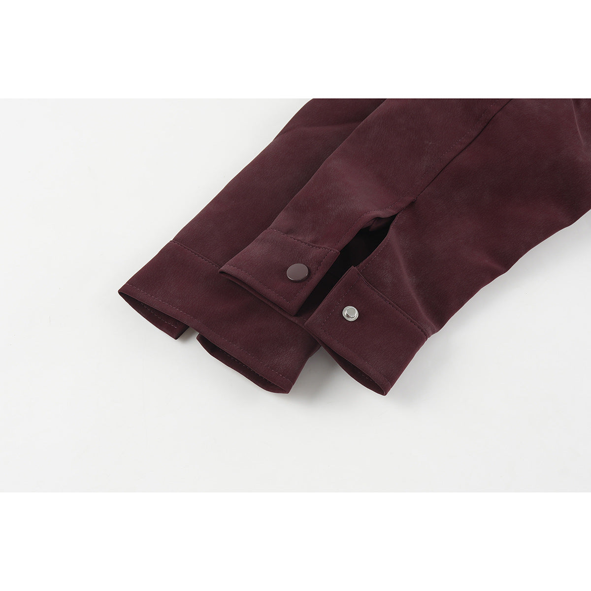 Close-up of burgundy jacket sleeve cuffs with snap buttons and layered panels.