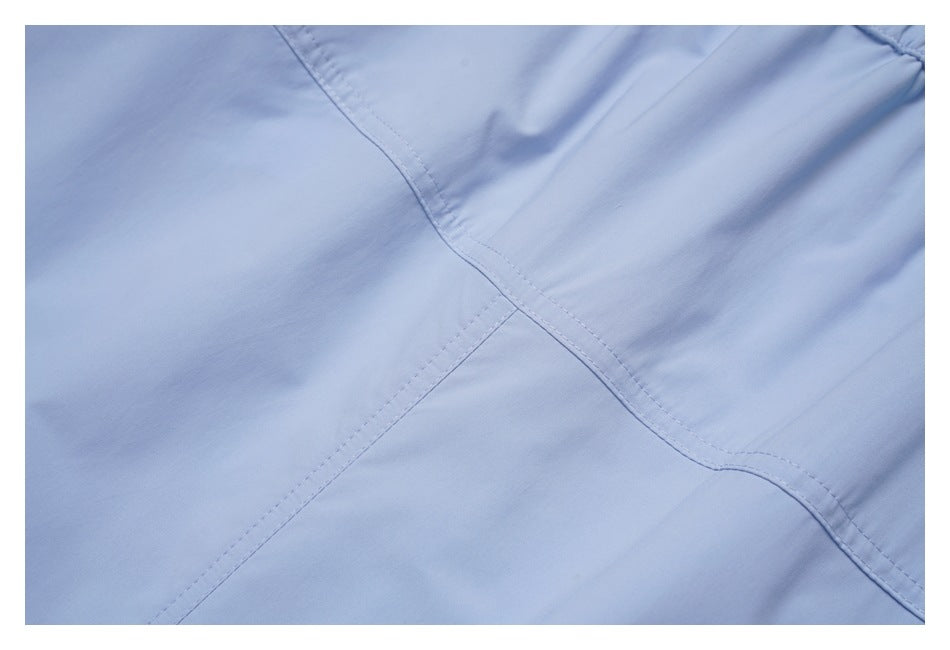 Close-up of pale blue fabric with intersecting double-stitched seams.
