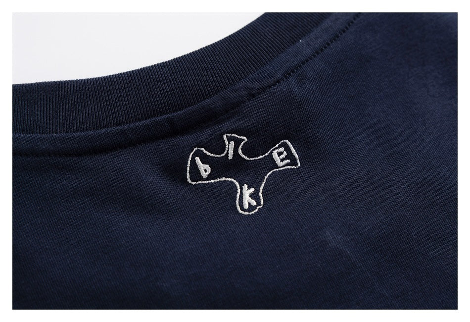 Close-up of a white embroidered outline emblem below the ribbed collar of a navy shirt.