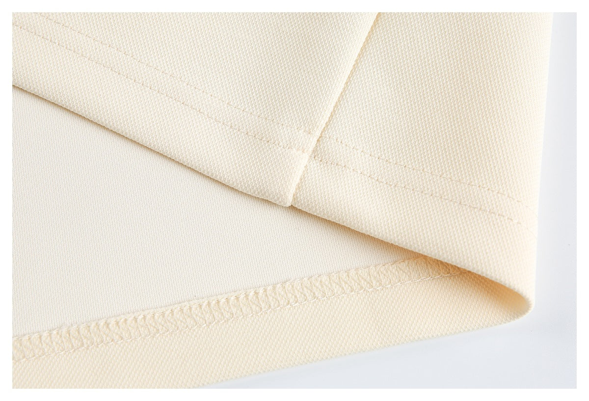 Close-up of a cream garment hem with visible stitching and an overlocked edge.