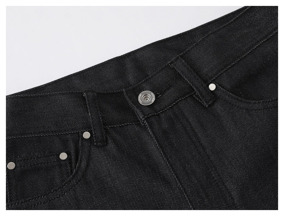 Close-up of black pants showing the front waistband, metal button, fly stitching and riveted pocket details.