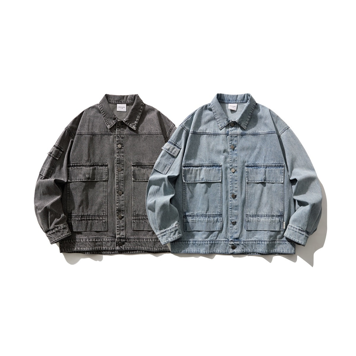 Front view of two denim jackets: one charcoal gray and one light blue, both with button fronts and large flap pockets.