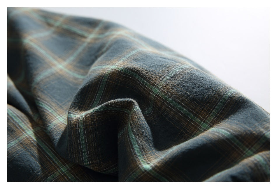 Close-up of dark blue-gray plaid fabric with muted green and tan intersecting lines.
