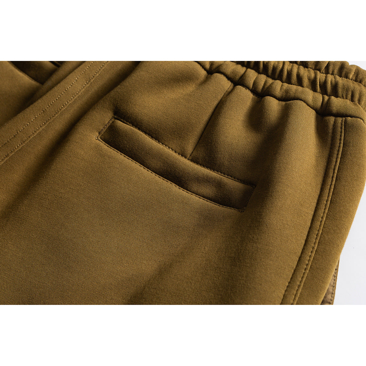 Close-up of mustard pants showing the elastic waistband and a slanted front pocket.