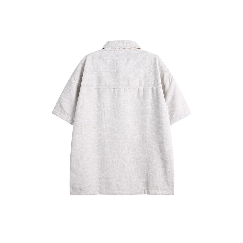 Back view of a pale gray patterned short-sleeve button-up shirt with a pointed collar and horizontal yoke seam.