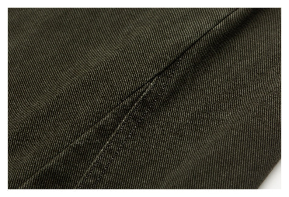 Close-up of dark olive trouser fabric with a diagonal stitched seam.