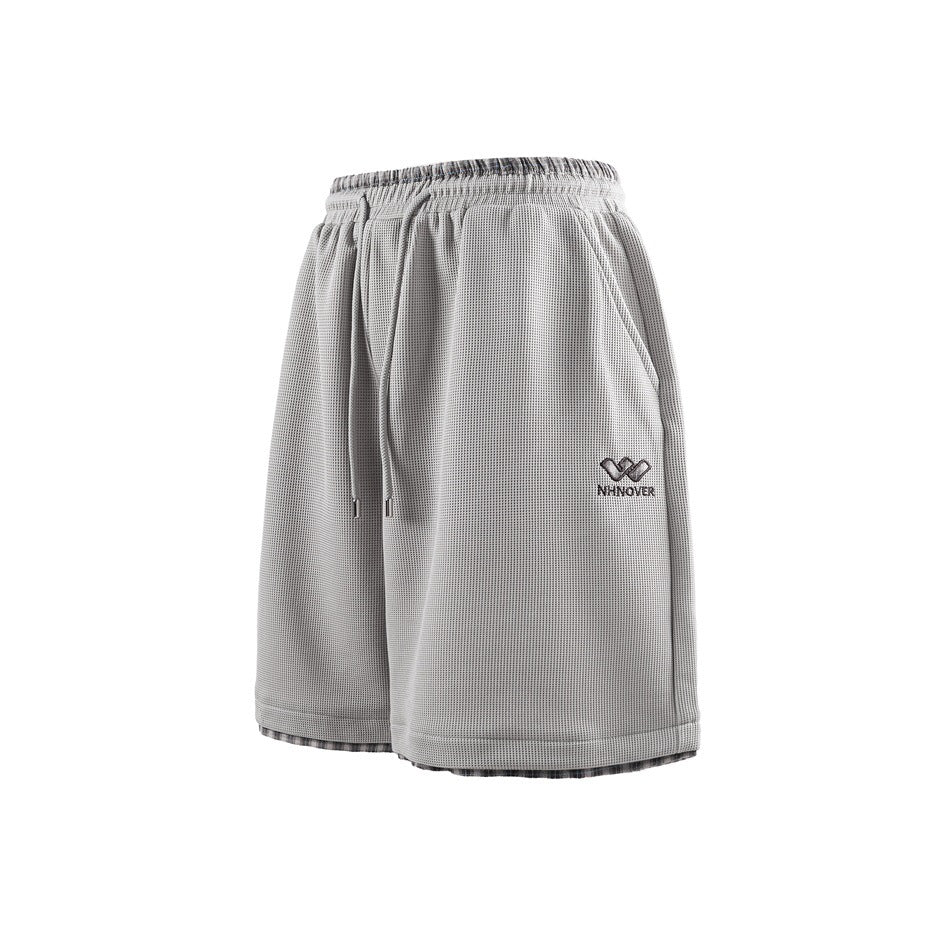 Light gray waffle-textured shorts, three-quarter front view, with drawstring waistband, side pocket and plaid inner hem