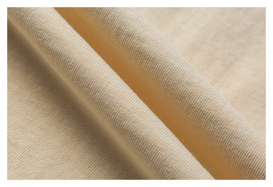 Close-up of light beige knit fabric draped in soft folds, showing its fine ribbed texture.