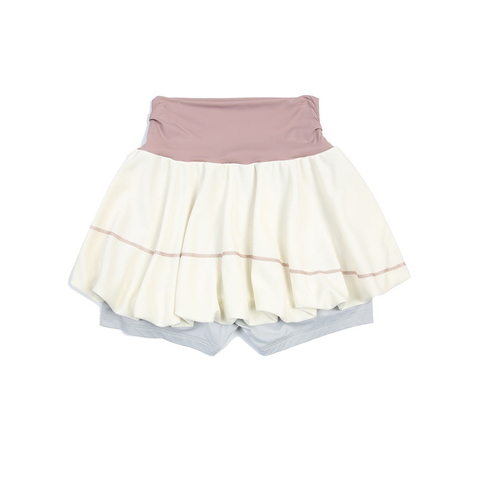 Flat lay of a cream bubble tennis skirt with a dusty pink waistband and pale gray built-in shorts.