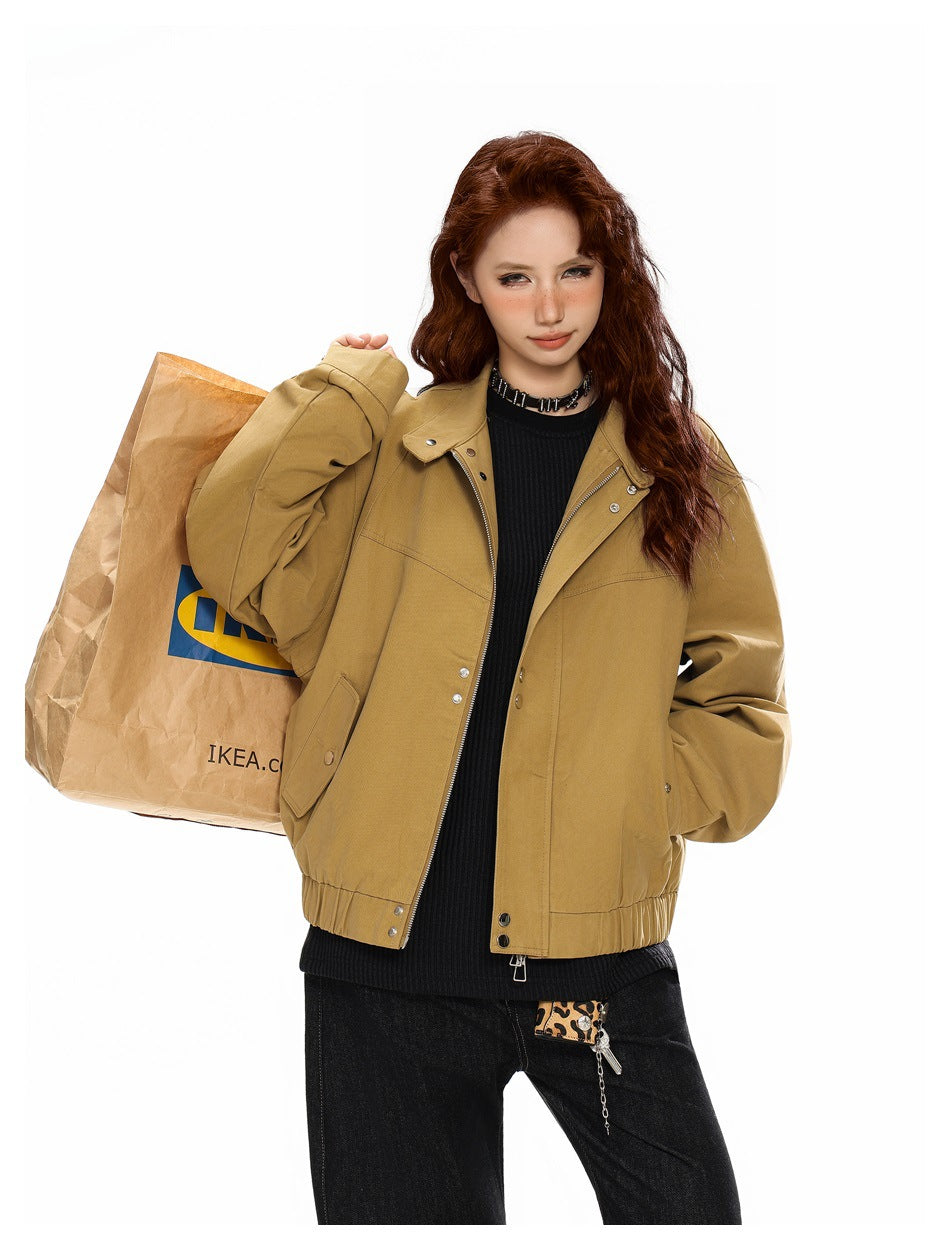 Model wearing an open khaki zip bomber jacket over a black knit top, carrying a large paper shopping bag