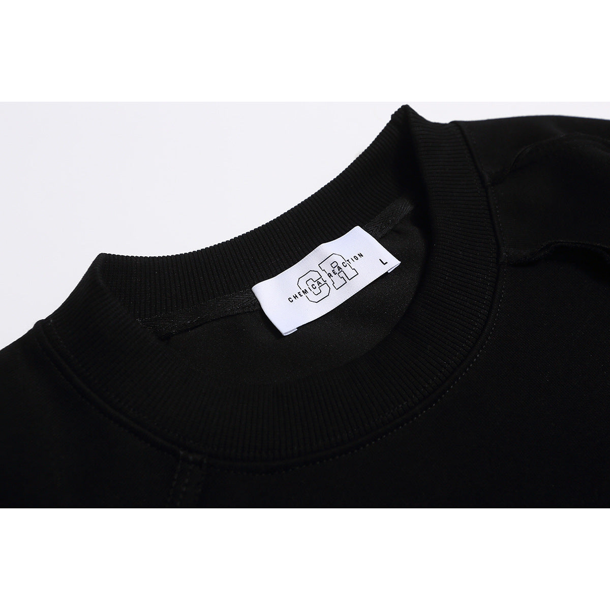 Close-up of a black sweatshirt’s ribbed crew neck and sewn-in white neck label.