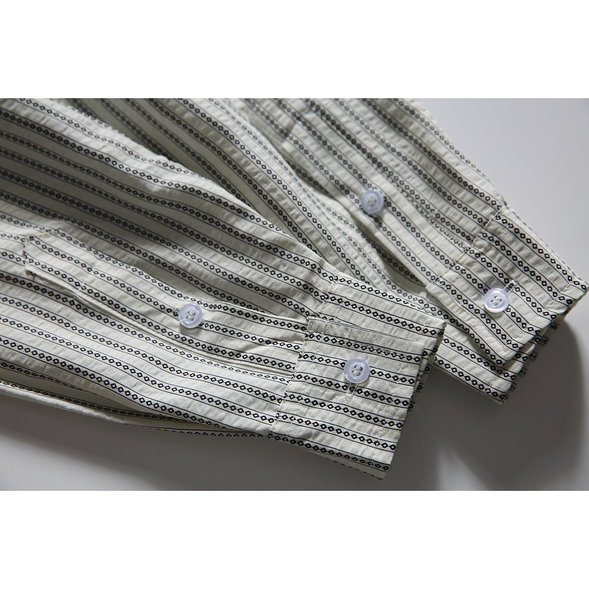 Close-up of the shirt's striped sleeve cuffs with white buttons and black geometric detailing.
