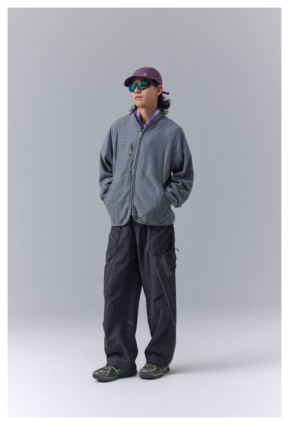 Model wearing a gray textured zip jacket with black cargo pants, shown standing.
