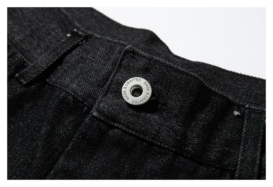 Close-up of the waistband and silver snap button on black denim.