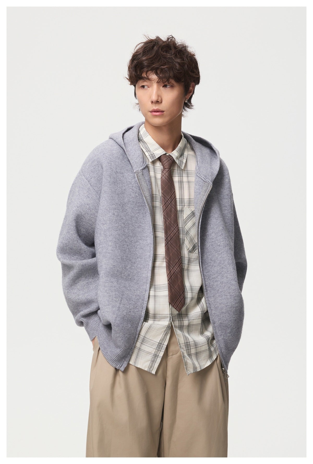 Model in a light gray hooded zip-up knit jacket, shown with a plaid shirt and tie.