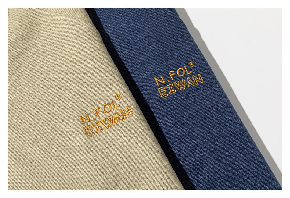 Close-up of gold embroidered lettering on beige and navy sweatshirt fabric.