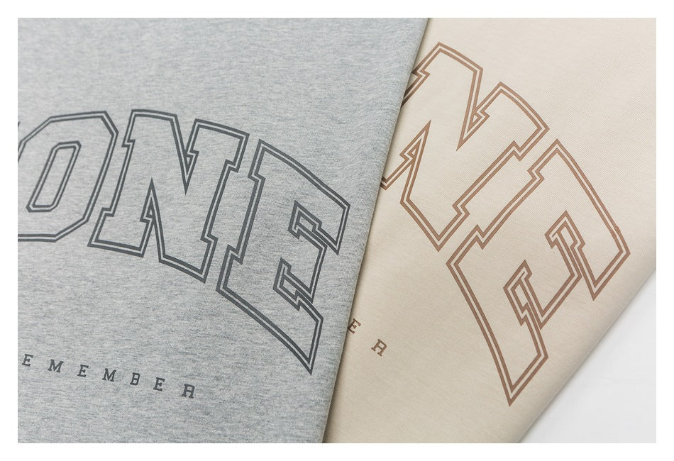 Close-up of outlined lettering printed on gray and cream T-shirts.