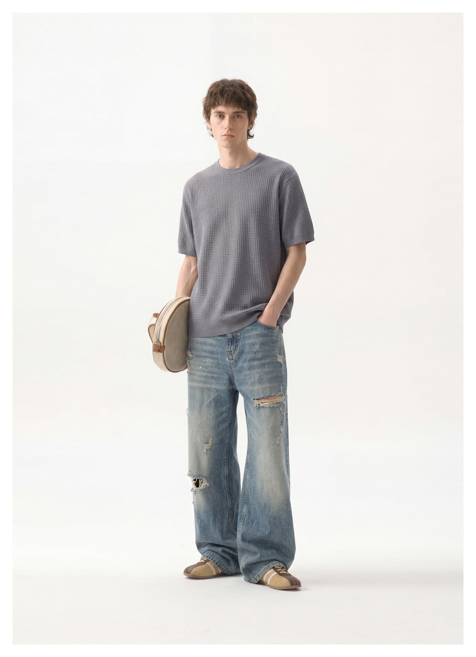 Model wearing a gray textured short-sleeve crewneck top with loose distressed blue jeans.