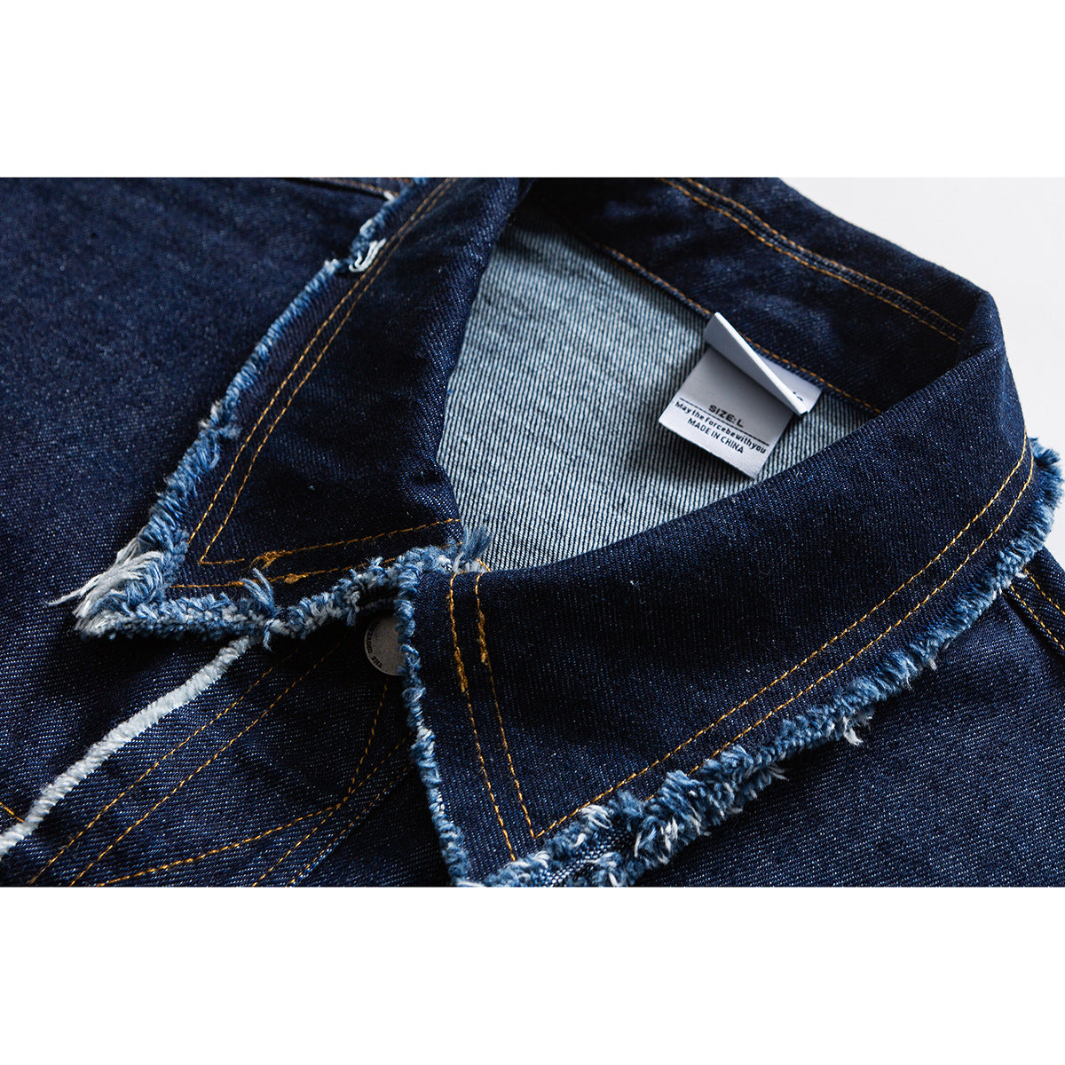 Close-up of a dark indigo denim jacket collar with frayed edges, gold stitching, and a size L label.