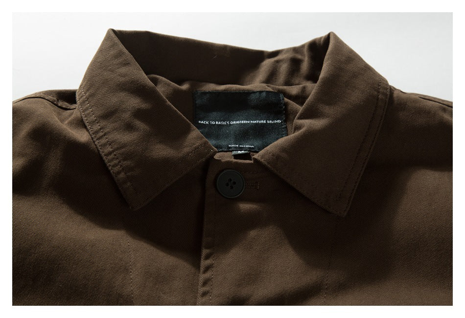 Upper front of a dark brown button-up shirt, showing its pointed collar and black button.