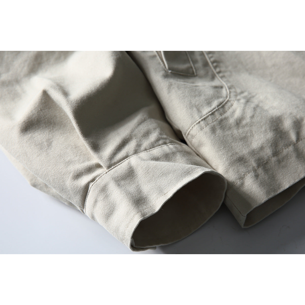 Close-up of an off-white jacket sleeve cuff and adjacent seam, showing the textured fabric.