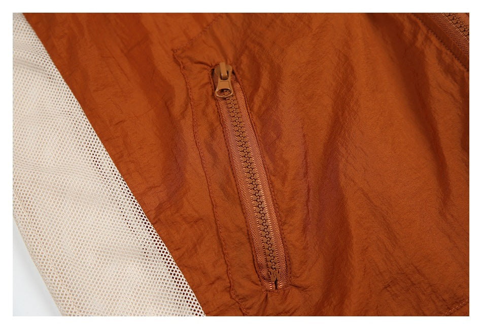 Close-up of a vertical zip pocket on rust fabric beside a pale mesh panel.