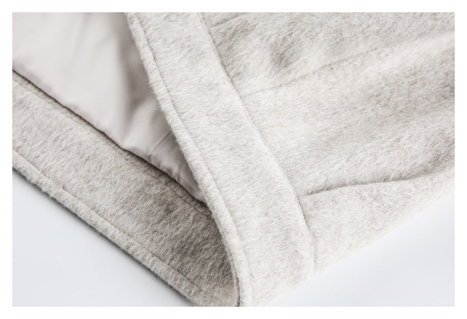 Close-up of a cream coat's edge, inner light lining, and stitched seam.
