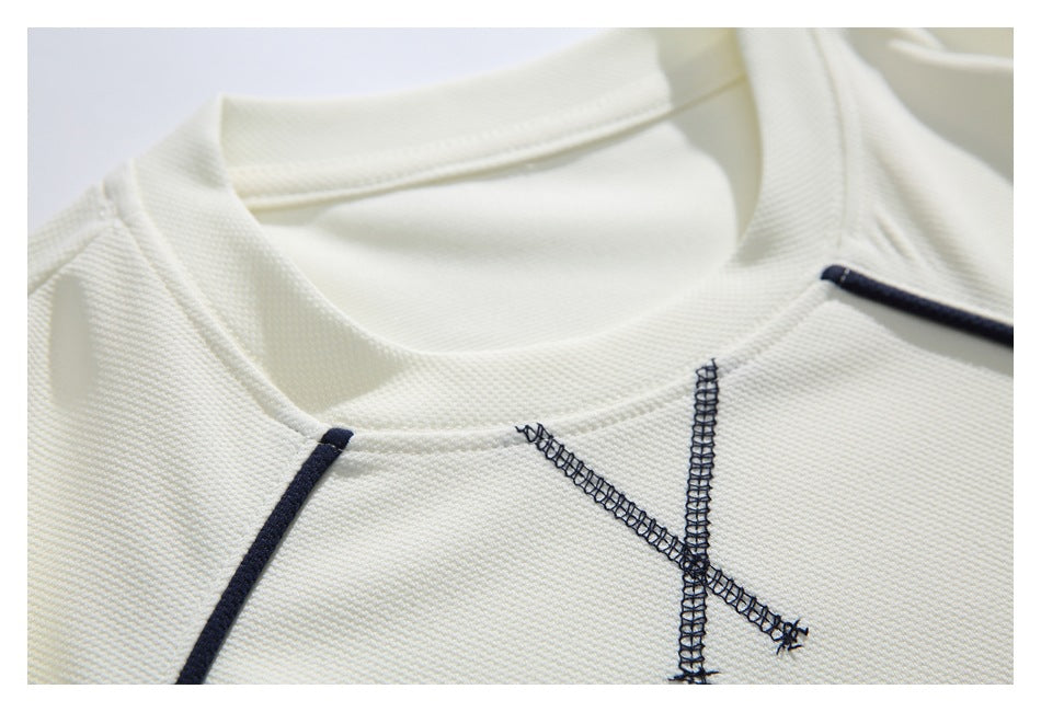 Close-up of an ivory shirt collar with dark navy piping and an intersecting decorative stitch motif.