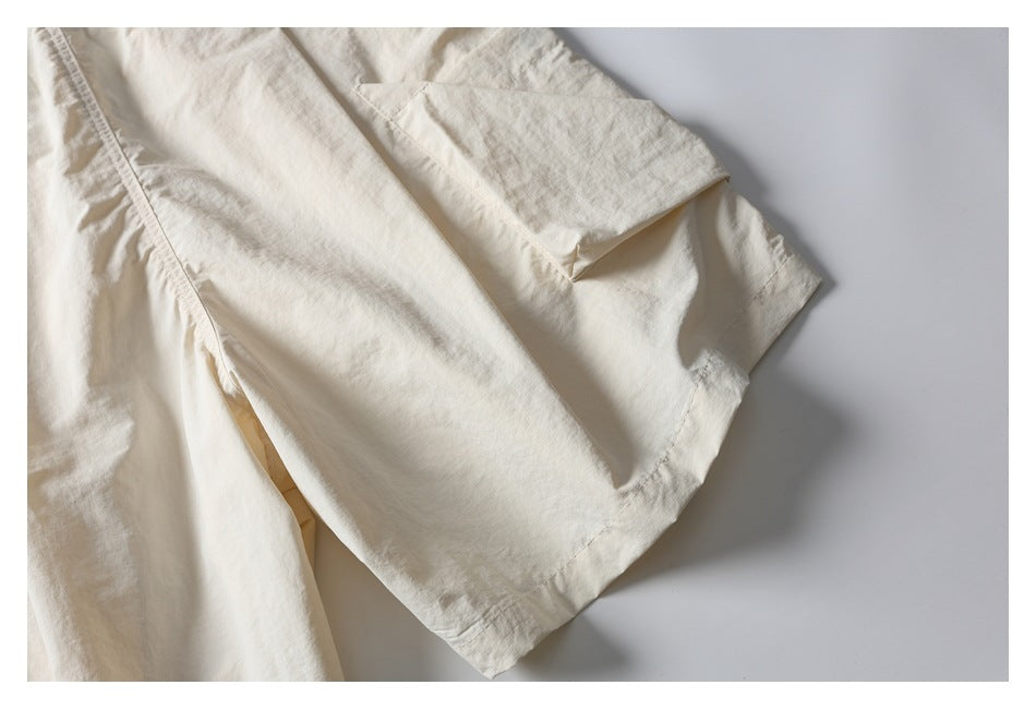 Close-up of an ivory shorts leg showing its loose shape, stitched hem, and side seam.