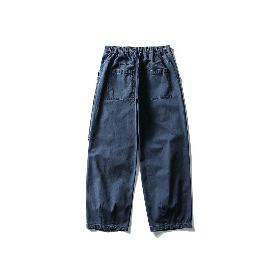 Back view of navy loose trousers with an elastic waistband, two patch pockets and gathered ankle hems.