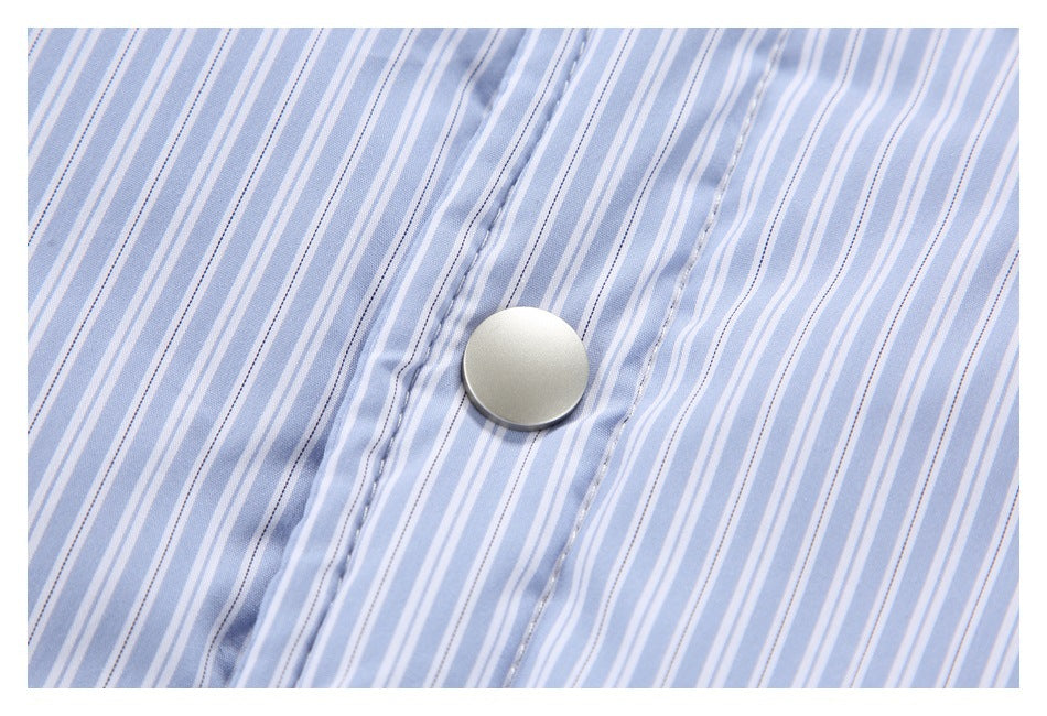Close-up of a round silver snap on the placket of a pale blue and white striped shirt.