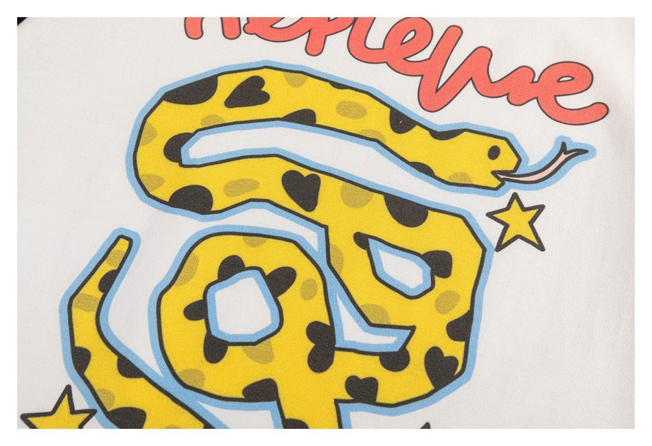 Close-up of a colorful yellow snake graphic with stars printed on an off-white T-shirt.