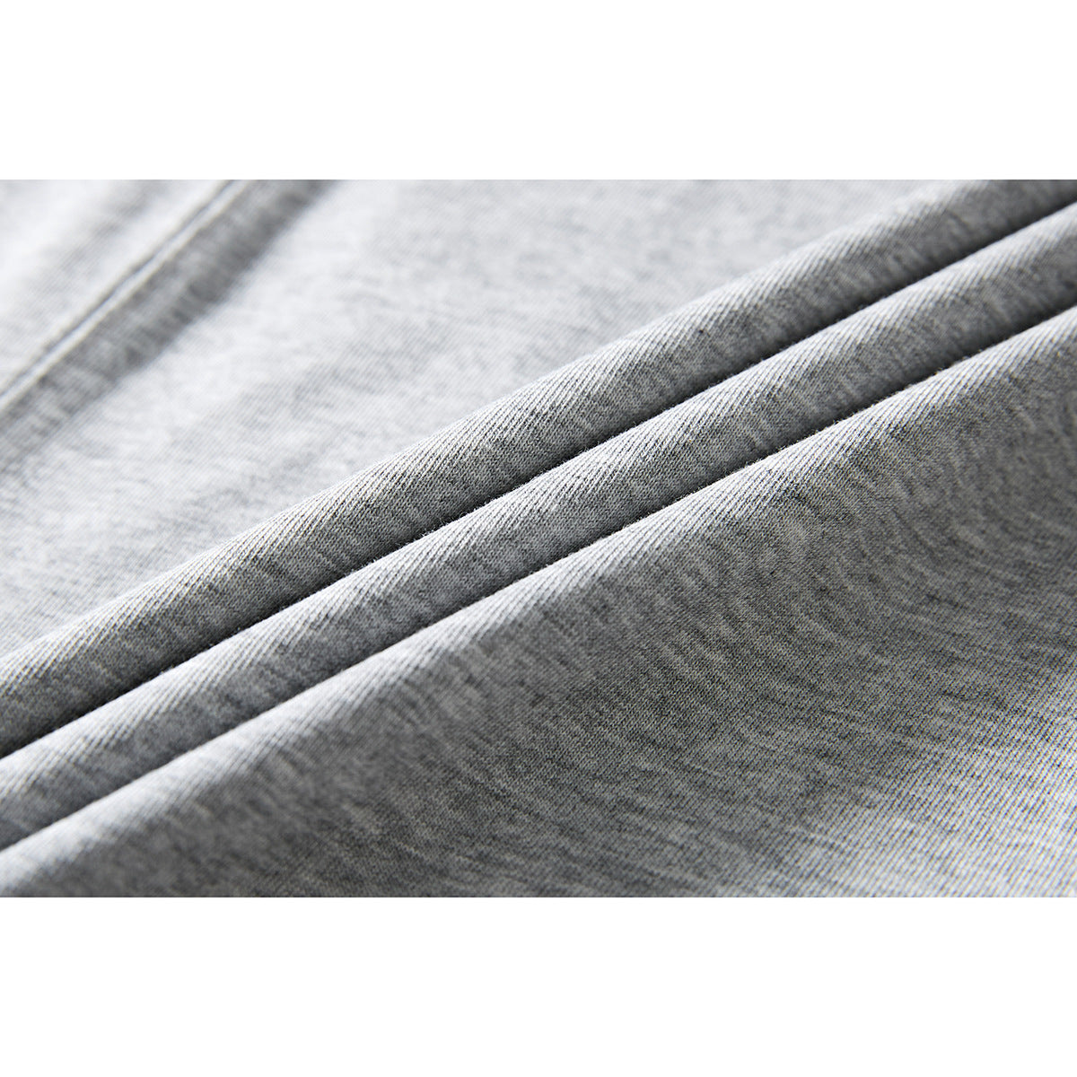 Macro view of light gray T-shirt fabric folded into ridges.