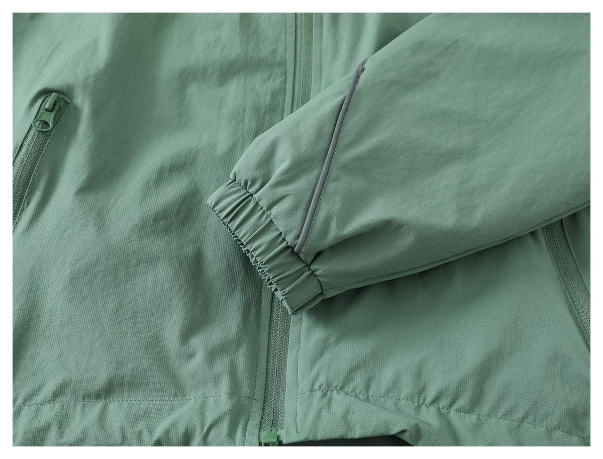 Close-up of a sage green jacket sleeve with an elasticated cuff and front zip details.